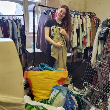 Image from Jayne's Baby Bank (main page), 1 Sep 2024: Chloe hanging up the £1 clothes in our pound shop level